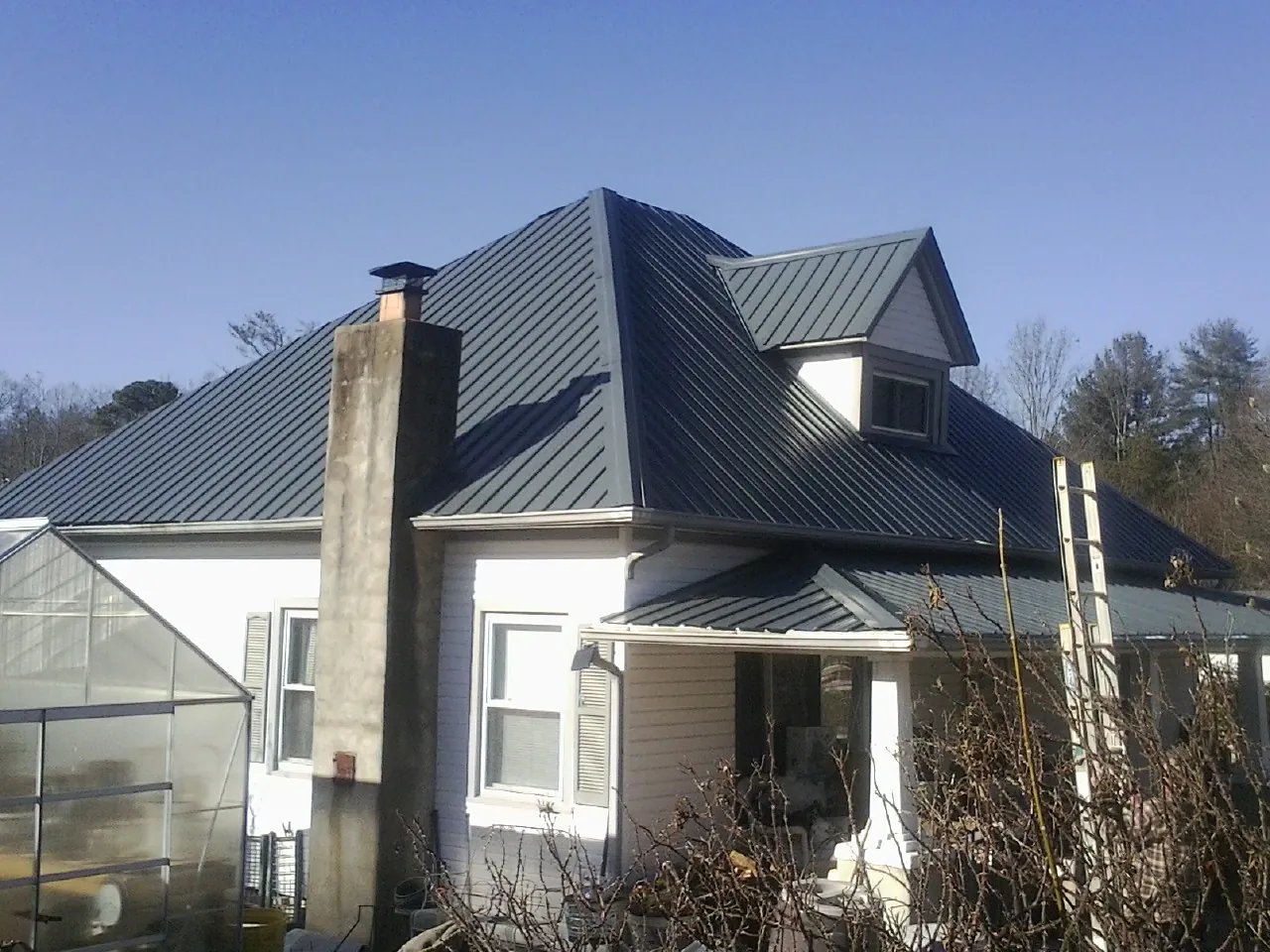 Dark blue standing seam metal roof on a white farmhouse with dormer — Slate & Tile Roof Repair by Roofing Brothers in Millers Falls