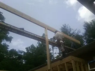Carpenter setting a ridge beam over a new addition frame in Millers Falls