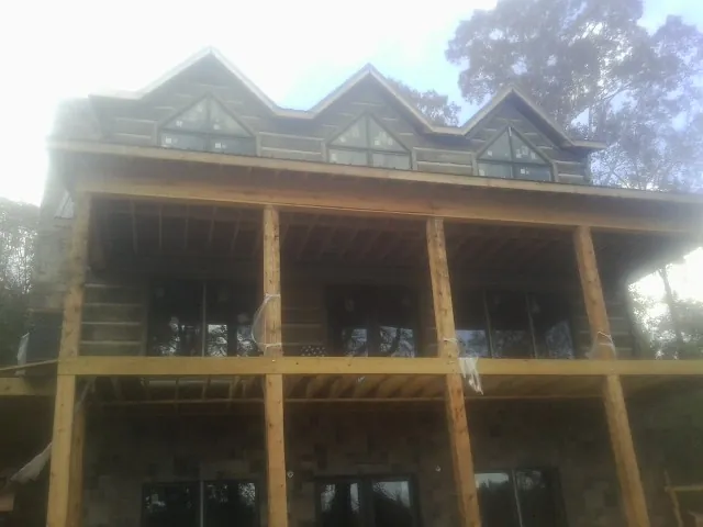Dormers and porch framing on a large log home under construction — Roof Coating work by our crew in Millers Falls