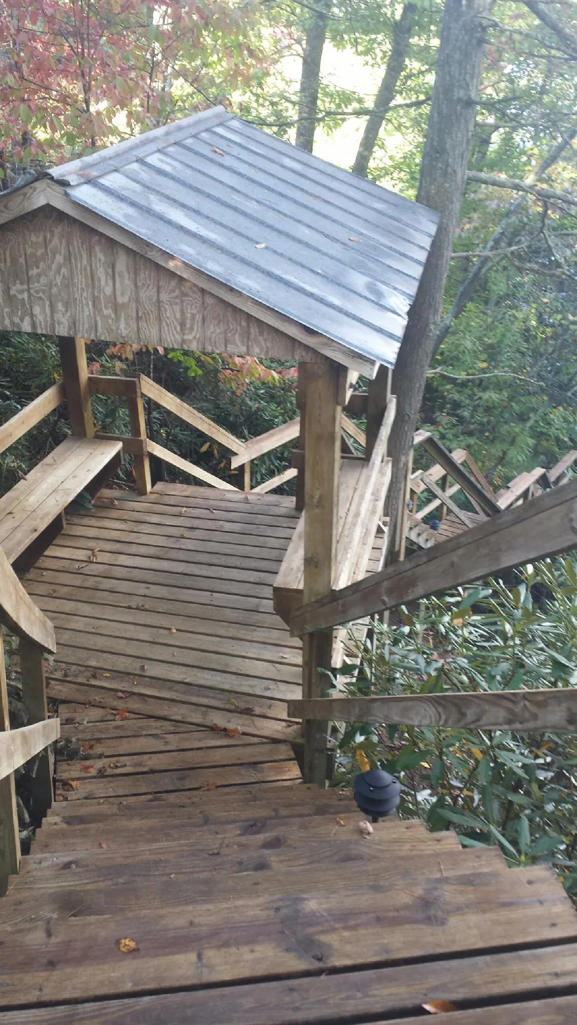 Metal roofed shelter over wooden steps on a wooded walkway — Skylight Repair & Installation work by our crew in Millers Falls