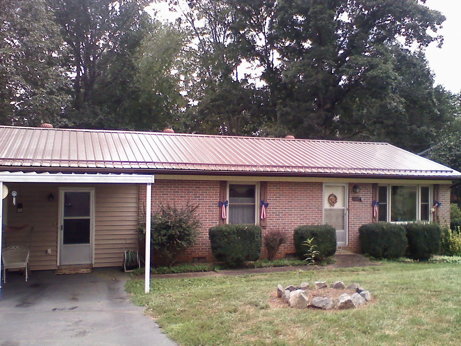 Bronze metal roof and carport on a brick ranch home — Roof Repair work by our crew in Millers Falls